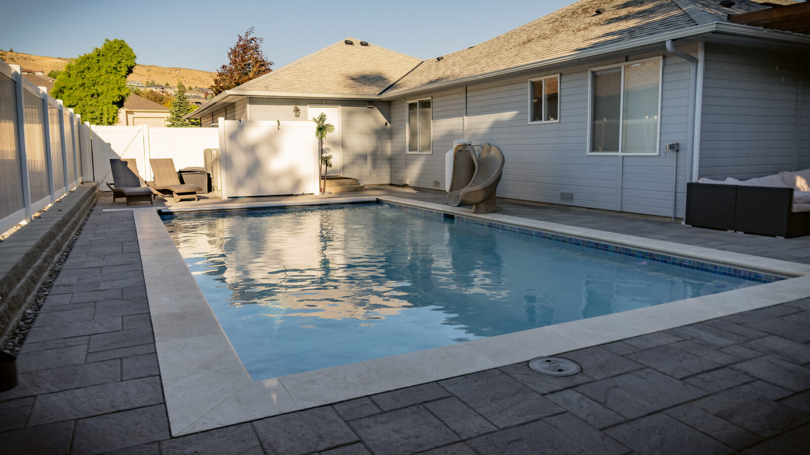 Backyard custom pool with paver deck at sunset