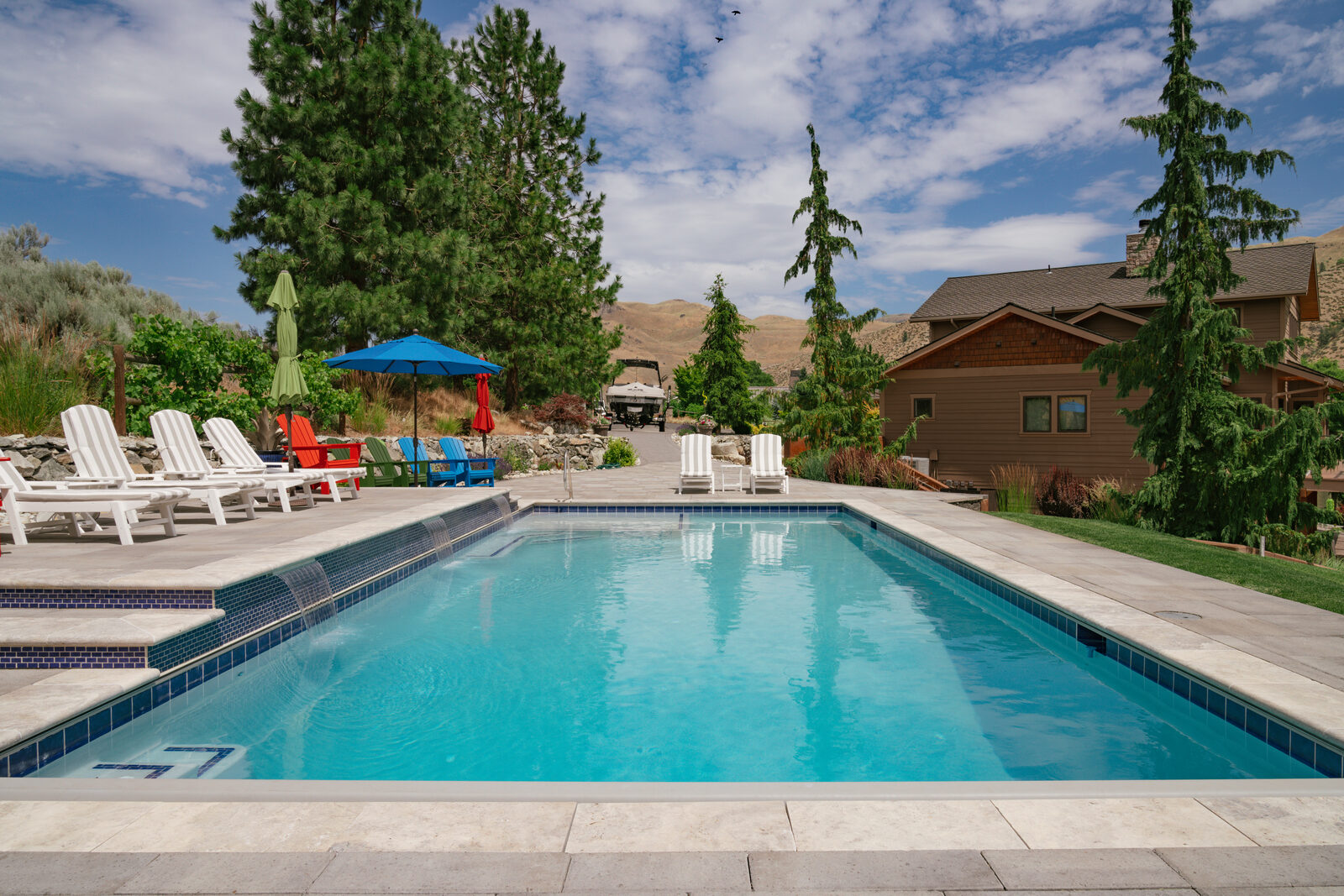 Custom pool surrounded by evergreens with log home