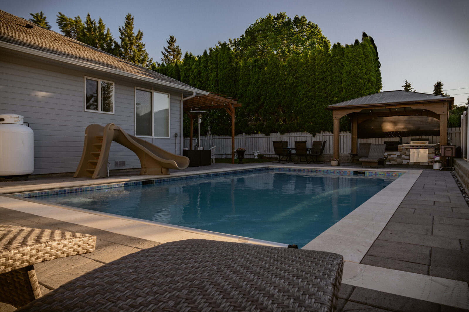 Custom pool with outdoor kitchen, pergola, and paver patio