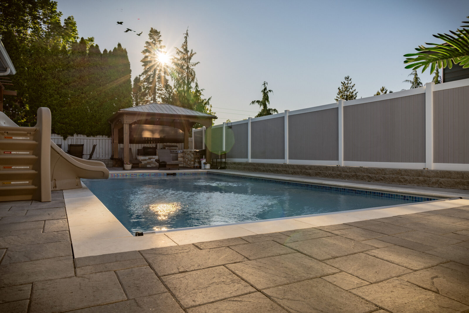 Custom pool with gazebo and paver patio at golden hour