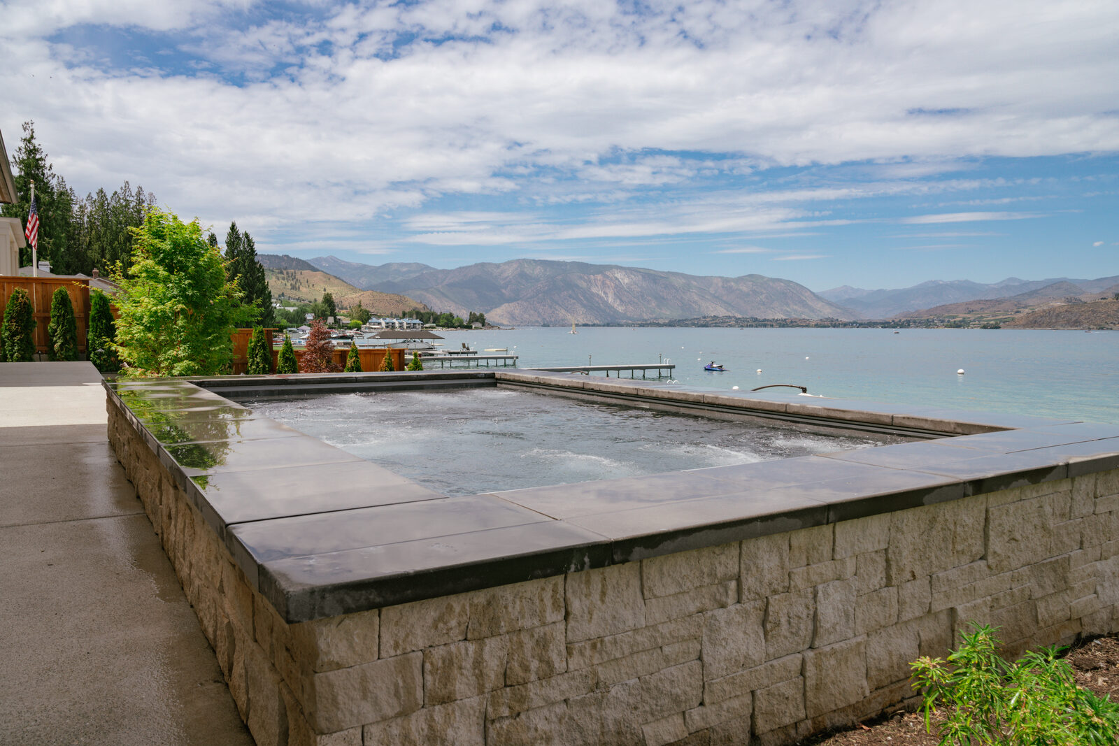 Raised custom spa with stone wall and waterfront view