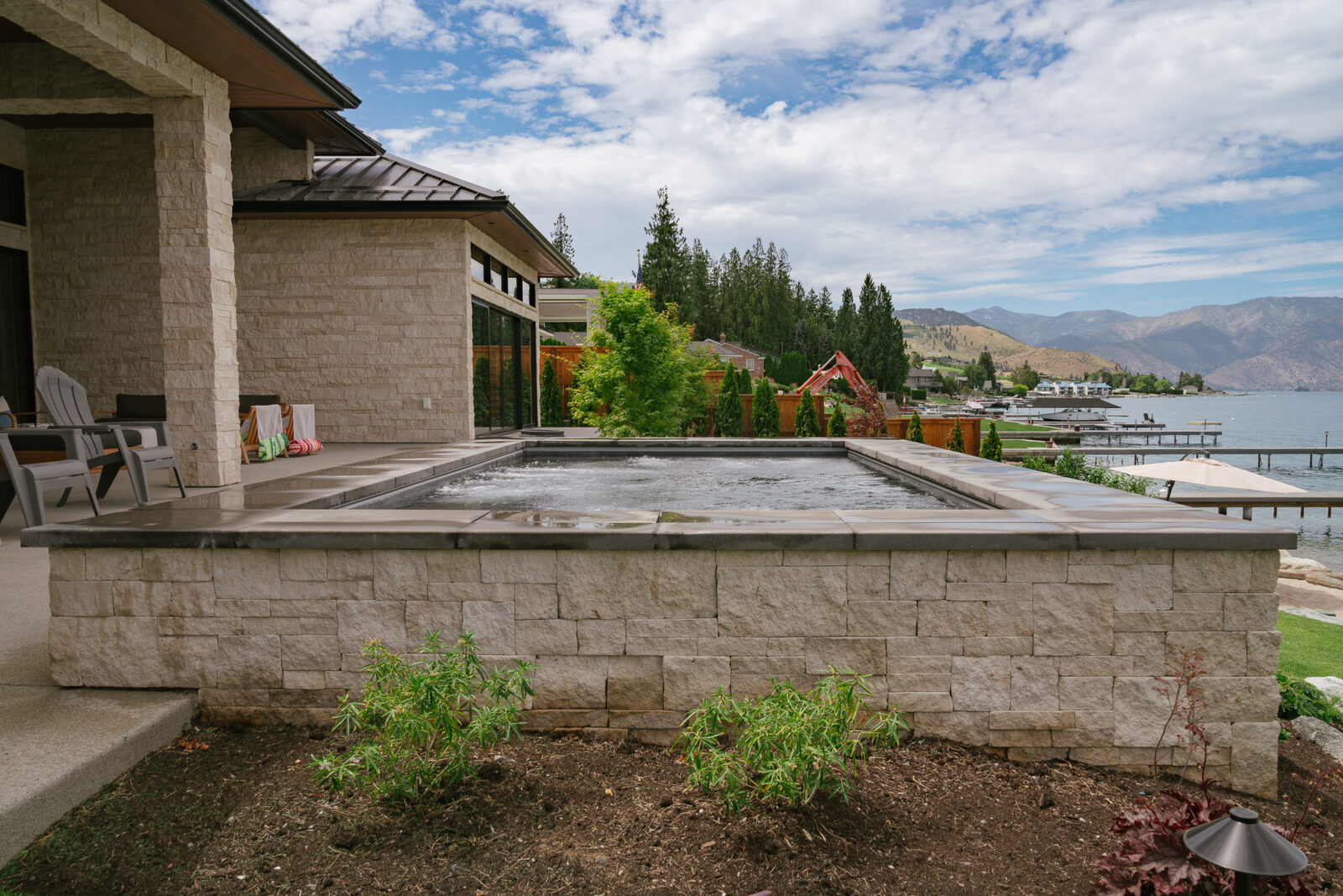 Raised custom spa next to stone-clad home