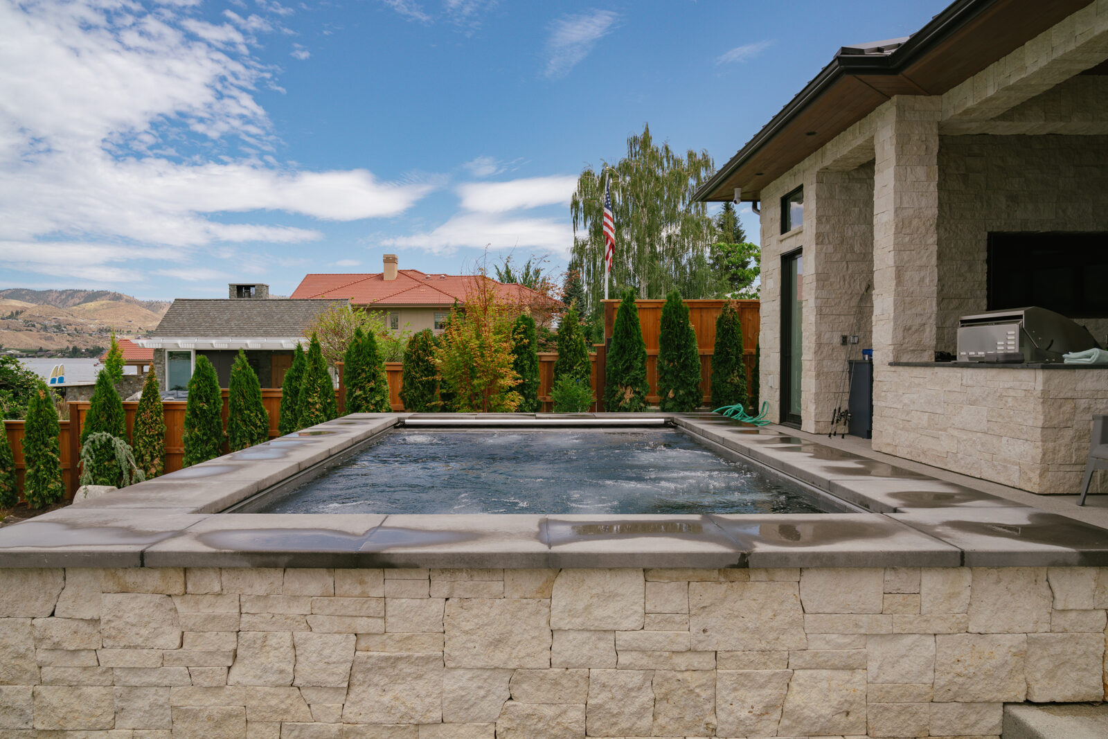 Custom spa with outdoor kitchen and stone home